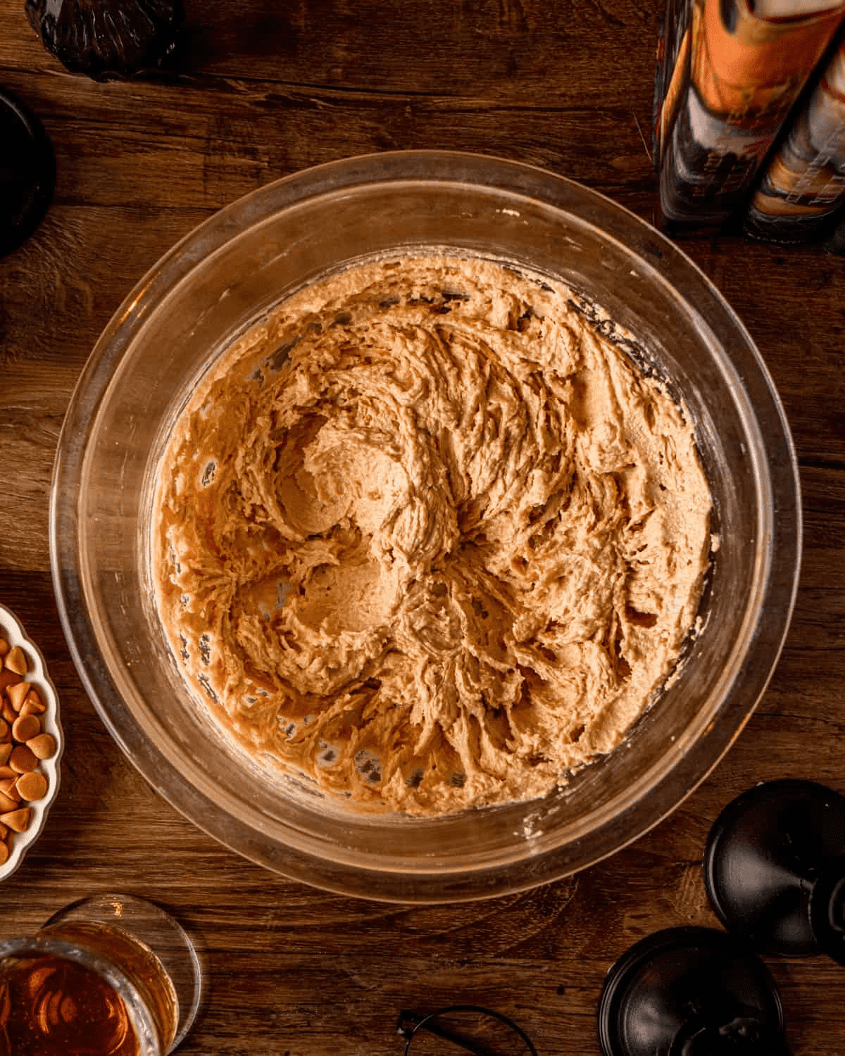 The mixing bowl after the egg yolks, extracts, and melted butterscotch chips are beaten in — darker amber tan with a paddle swirl through the middle.