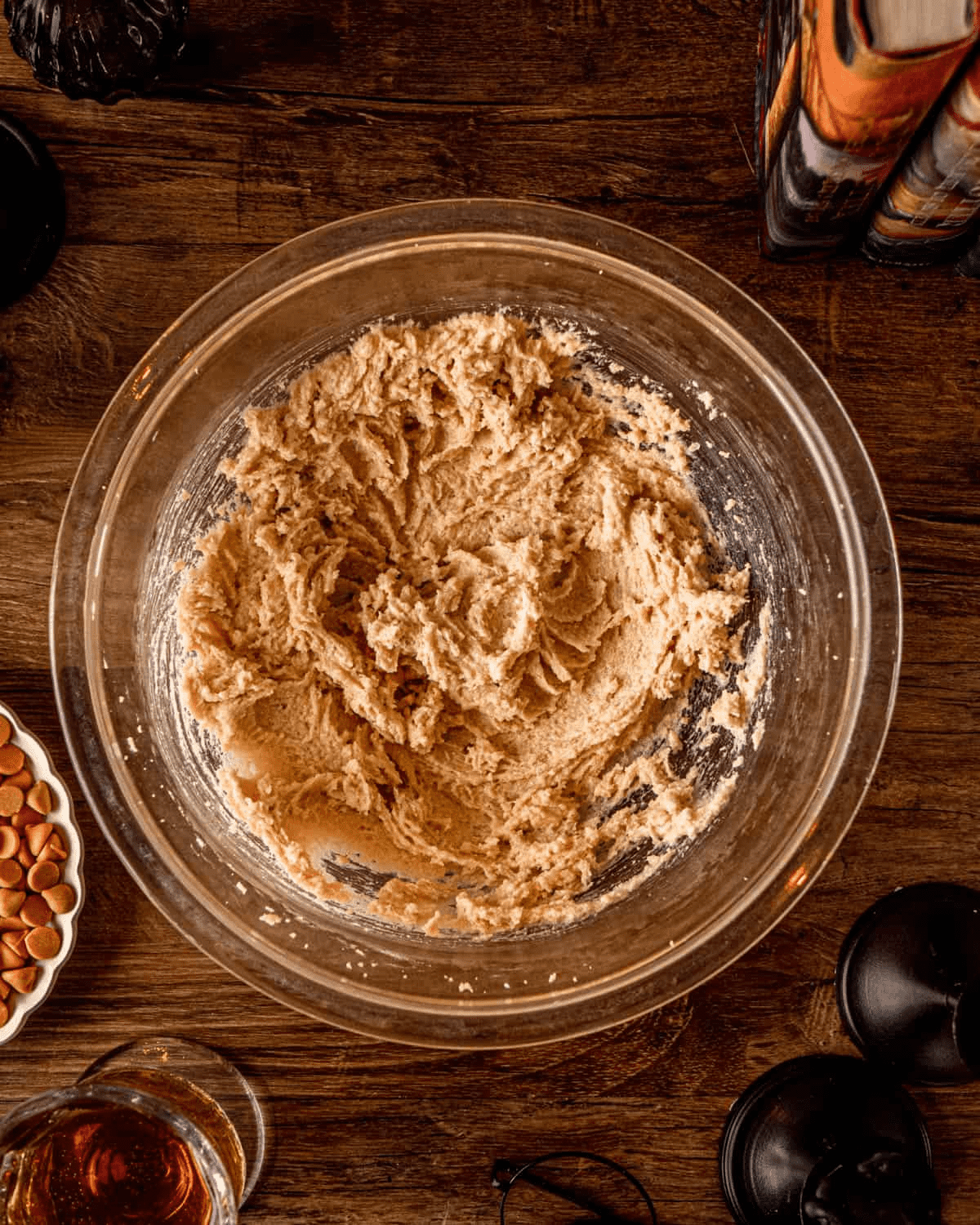 Creamed butter and sugars in a glass mixing bowl — pale tan, smooth, fluffy from 3 minutes on high speed.