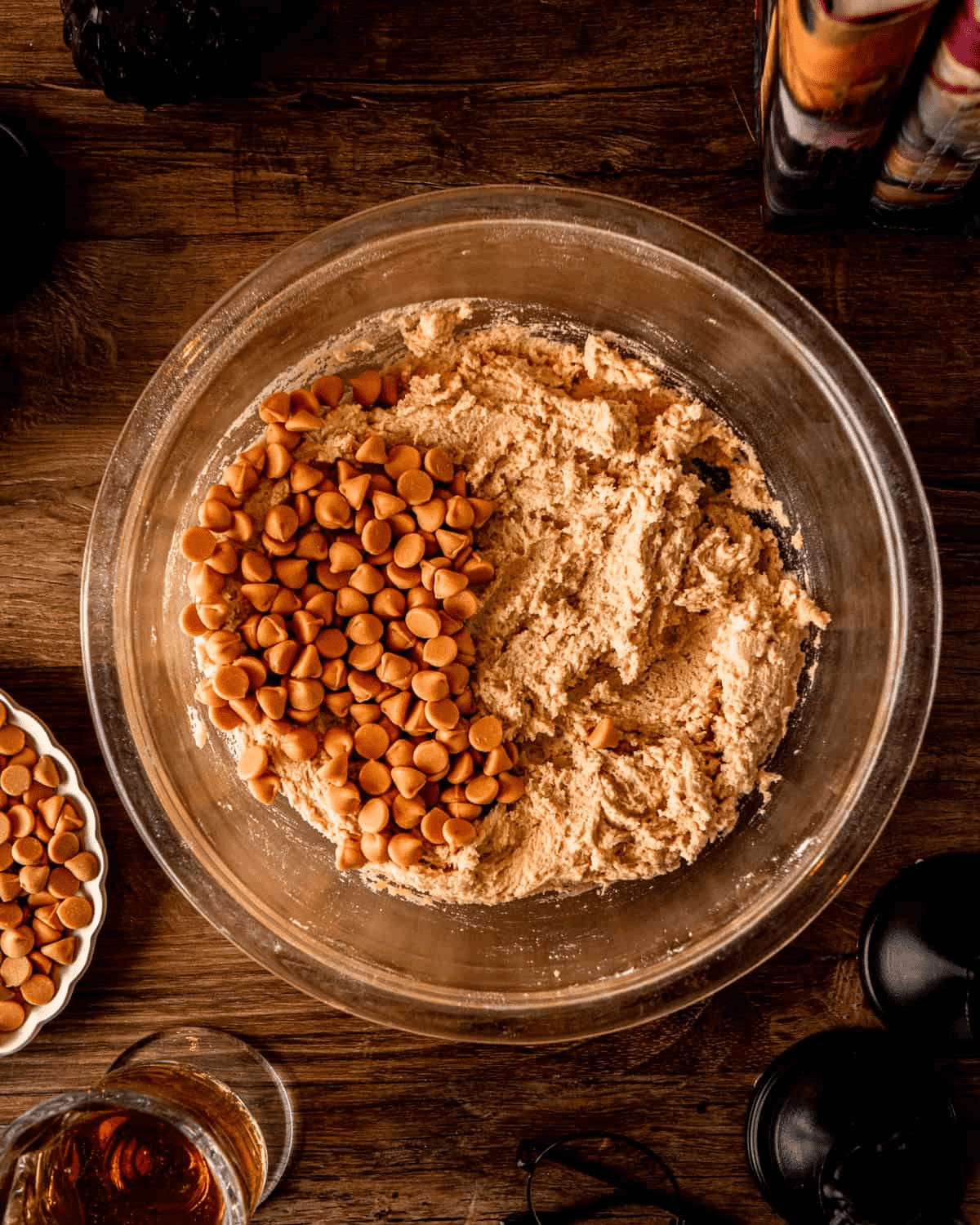 A pile of whole butterscotch chips on top of the dough, ready to be folded in by hand.