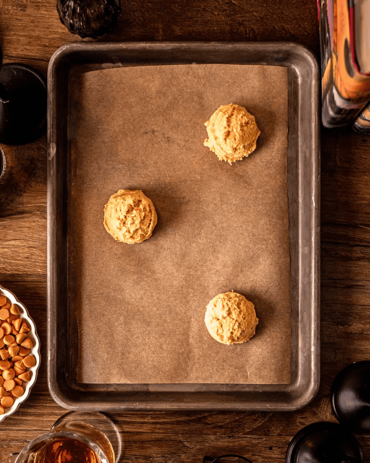 Three 2-tablespoon balls of cookie dough spaced on a parchment-lined baking sheet, 2 inches apart.