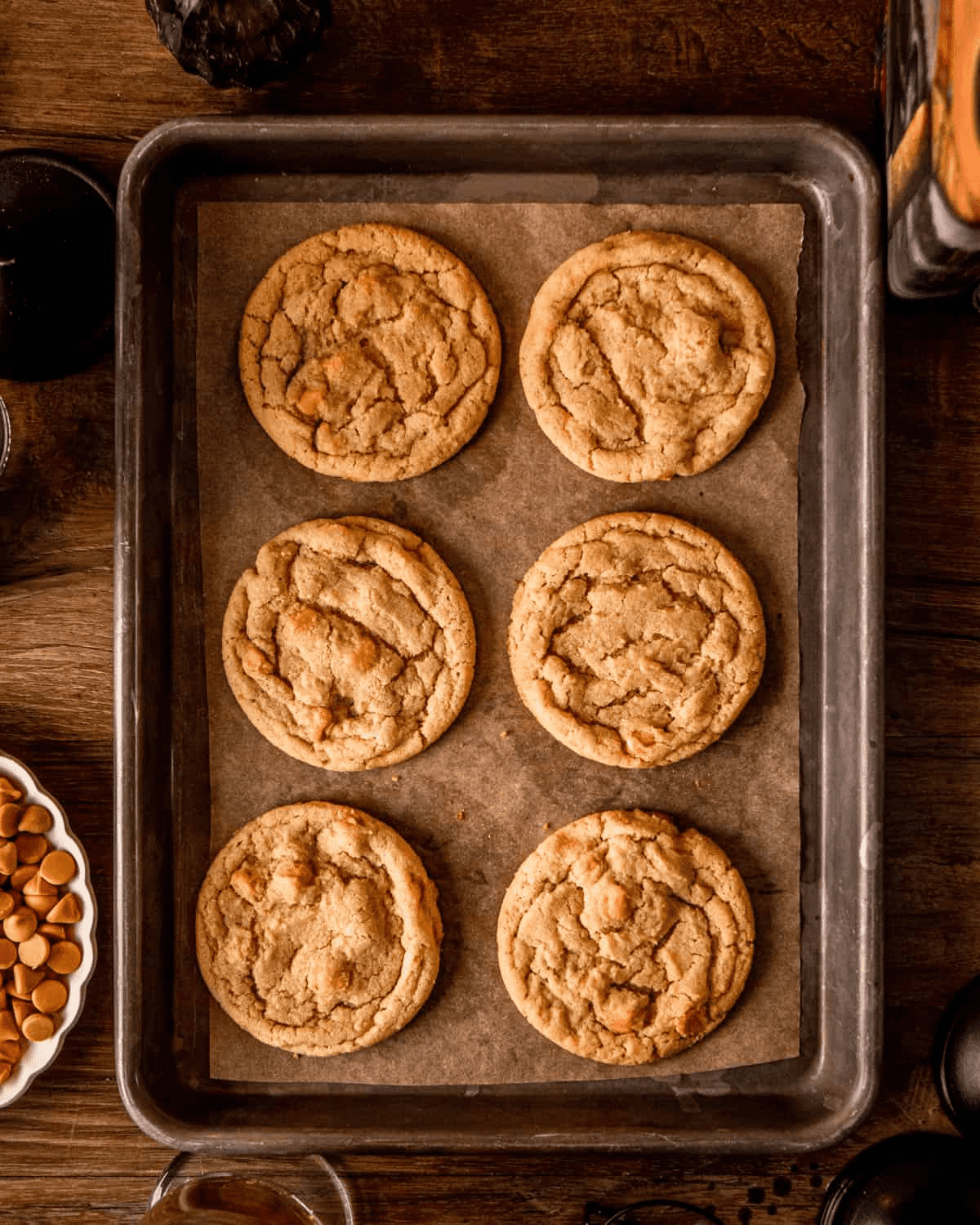 Six baked butterbeer cookies on the sheet pan — golden edges, slightly crackled tops, soft centers.